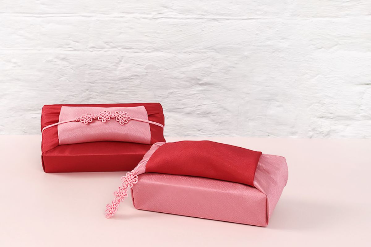 two rectangular boxes wrapped with red and pink color Bojagi.
